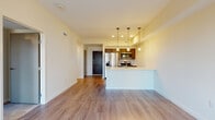 Located at 144 S Main St in the heart of downtown Akron, Ohio, this single-floor unit offers a thoughtfully designed open-concept layout with modern finishes throughout. The living and dining area features smooth hardwood-style flooring, warm neutral walls, and recessed lighting, creating a bright and welcoming atmosphere.

The kitchen is a standout feature, equipped with stainless steel appliances including a French door refrigerator, electric range, and built-in microwave. Dark espresso cabinetry contrasts elegantly with the marble-inspired quartz countertops, while a peninsula with a stainless undermount sink and pendant lighting serves as both a functional workspace and a natural divider between the kitchen and living area.

The bedroom is carpeted for comfort and features a large window with roller shade that frames views of the surrounding downtown Akron skyline, allowing generous natural light to fill the room. A ceiling fan adds to the room's functionality.

The bathroom is well-appointed with a dark wood vanity, illuminated mirror, tile flooring, and a full walk-in shower enclosed by sliding glass doors with large-format tile surround. A dedicated in-unit laundry area with a stacked washer and dryer adds everyday convenience. The overall design is clean, contemporary, and well-suited for urban living.
