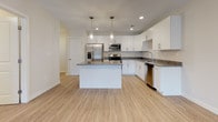 This single-floor residence at 243 Talcottville Rd in Vernon Rockville, Connecticut, presents a clean, contemporary design with thoughtfully selected finishes throughout. The open-concept layout connects the kitchen and living areas seamlessly, creating a bright and functional living environment.

The kitchen serves as a central highlight, showcasing white shaker-style cabinetry, granite countertops, and a generous island with additional granite surface space. Stainless steel appliances, including a refrigerator with ice maker, range, microwave, and dishwasher, complement the space. Light wood-tone flooring and pendant lighting add warmth and style to the kitchen area.

The living room is generously sized, featuring the same light wood-tone flooring and a sliding glass door that introduces natural light and provides outdoor access, offering pleasant views of the surrounding greenery.

The bedrooms are carpeted in a neutral tone, providing comfort underfoot. Each bedroom features ample closet space, including walk-in and double-door closet configurations. The neutral wall tones and recessed HVAC venting maintain a clean, modern aesthetic throughout each room.

Overall, the unit presents a well-coordinated, move-in-ready interior with consistent finishes, functional design, and a bright, open ambiance.