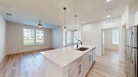 Located in Sherman, TX, this well-appointed single-story home offers 2 bedrooms and 2 bathrooms within a thoughtfully designed open-concept floor plan. Light hardwood-style flooring flows throughout, complementing the clean, neutral color palette that gives the home a bright and modern feel.

The heart of the home is the open kitchen, dining, and living area. The kitchen features a large center island with quartz countertops, an undermount sink with a matte black faucet, light wood-toned cabinetry, a tile backsplash, and stainless steel appliances including a refrigerator, microwave, and range. Pendant lighting above the island adds a contemporary touch. The adjacent living area benefits from multiple windows that invite natural light and outdoor views, enhanced by a ceiling fan overhead.

Both bedrooms are generously proportioned, each with large windows offering exterior views and durable hardwood-style flooring. The primary bedroom includes access to a walk-in closet for added convenience. The primary bathroom is a standout, featuring a dual-sink vanity with granite countertops, white cabinetry, and a tiled walk-in shower.

Additional highlights include multiple closets, a dedicated laundry area, a utility room, a welcoming entrance, and a patio for outdoor enjoyment.