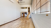 Located at 408 S Frankfort Ave in Tulsa, OK, this two-story urban loft offers a distinctive industrial-modern aesthetic spread across two equally sized floors. The main level greets you with soaring ceilings, polished concrete floors, and large windows fitted with horizontal blinds that fill the open living area with natural light. Exposed concrete ceilings, a wall-mounted mini-split system, and a wood-and-metal staircase add to the loft's contemporary industrial character. The kitchen is a standout feature, showcasing dark espresso cabinetry, stainless steel appliances including a full refrigerator, electric range, and microwave, complemented by granite countertops and a functional center island with a built-in sink and pendant lighting overhead. The upper floor houses the generously sized primary bedroom, which features warm hardwood flooring, an exposed concrete ceiling with track lighting, and windows offering views of the surrounding Tulsa skyline. A dedicated closet provides practical storage. The full bathroom is finished with neutral tile, a tub/shower combination, dark cabinetry, and granite countertops, maintaining the cohesive modern palette found throughout the space. This loft delivers a compelling blend of urban industrial design and functional, comfortable living.