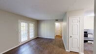 Located at 3725 Fountain Ave in East Ridge, Tennessee, this single-floor residence offers a practical and well-organized layout comprising a living room, one bedroom, and a closet. The living room is a standout feature, finished with rich, dark hardwood-style flooring that adds warmth and character to the space. A set of classic French doors floods the room with natural light and provides views of the surrounding greenery, creating an inviting and open atmosphere. Neutral, light-toned walls throughout the home contribute to a clean and versatile aesthetic. The generously proportioned primary bedroom is finished with soft wall-to-wall carpeting and features a window that allows natural light to filter in, enhancing its comfortable feel. A textured ceiling adds subtle detail overhead, while a dedicated closet provides practical storage. The kitchen area, visible in the overview, is neatly positioned toward the rear of the floor plan. Overall, the space presents a straightforward, functional design with a neutral palette, making it a versatile canvas adaptable to a variety of interior styles.