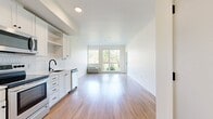 This 530-square-foot, one-bedroom, one-bathroom apartment is located on the ground floor at 7900 SE Luther Road in Portland, OR. The open-concept kitchen and living area is bright and airy, featuring light wood-tone flooring throughout and large floor-to-ceiling windows that flood the space with natural light and offer views of lush greenery. A private exterior door in the living area provides direct outdoor access.

The kitchen is outfitted with white shaker-style cabinetry, a white hexagonal tile backsplash, and a full suite of stainless steel appliances, including a refrigerator, electric range, over-the-range microwave, and dishwasher. Ample upper and lower cabinet storage adds functionality.

The 120-square-foot bedroom continues the light wood flooring and features a large window framing outdoor green views. A dedicated closet provides organized storage. The bathroom includes a full soaking tub with shower, a dark-cabinet vanity, and wood-tone flooring, maintaining the clean, modern aesthetic found throughout the unit.

A wall-mounted HVAC unit in the living area ensures year-round climate comfort. Clean white walls, consistent flooring, and an abundance of natural light create a cohesive, modern ambiance throughout this efficiently designed Portland apartment.