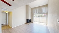 This two-bedroom, two-bathroom home is thoughtfully arranged across two floors, offering a functional and comfortable layout. The main level features a spacious living area with vaulted ceilings that create an open, airy atmosphere. A corner fireplace serves as a focal point, while large sliding glass doors flood the room with natural light and provide outdoor views. Light-toned laminate flooring runs throughout the main living areas, complementing the neutral, warm wall tones. The kitchen features speckled granite-style countertops, ample cabinetry, and efficient use of space. Two full bathrooms are included, each equipped with a shower-tub combination, overhead cabinetry, and speckled countertop vanities with large mirrors. The bedrooms offer comfortable proportions, with the primary bedroom situated on the upper floor, featuring plush carpeting, a ceiling fan, a closet, and a window with vertical blinds for natural light. The second bedroom is located on the main floor and also benefits from natural light via a large window. Textured ceilings are present throughout, and the home includes four hallways and two closets for added storage. The overall ambiance is clean, bright, and move-in ready, with a neutral palette that suits a variety of interior styles.