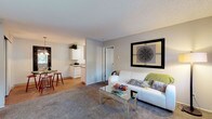 Located at 15301 NE 20th Street in Bellevue, Washington, this single-floor residence offers a well-organized layout designed for comfortable everyday living. The living room serves as the heart of the home, featuring plush carpet, a large window that frames views of the surrounding Pacific Northwest trees, and a welcoming entry with wood-style flooring at the front door. The space flows naturally into a dedicated dining area, illuminated by a pendant chandelier and set adjacent to a convenient in-unit stacked washer and dryer tucked behind a sliding door. The galley-style kitchen is efficiently designed with white cabinetry, laminate countertops, wood-style flooring, and a full suite of white appliances including a refrigerator, electric range, and dishwasher. Two carpeted bedrooms provide restful retreats; one features a walk-in closet, while the other enjoys a bright window with serene outdoor views and a baseboard heating unit. The bathroom includes a clean, full-size soaking tub and shower combination with built-in shelving. A secondary bathroom with wood-style flooring, a vanity, and toilet adds additional convenience. Neutral tones and textured ceilings throughout give the residence a consistent, understated aesthetic.