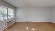 Located at 394 Boynton Ave in San Jose, CA, this single-floor unit offers a practical and efficient layout comprising a living room, kitchen, closet, and bathroom. The living room is bright and open, featuring light wood laminate flooring, neutral gray walls, and a textured popcorn ceiling. Natural light filters in through a window fitted with horizontal blinds, while a wall-mounted HVAC unit and a baseboard heater ensure year-round climate control. A entry door opens directly into the living area, enhancing accessibility. The kitchen is thoughtfully designed with white cabinetry, warm wood-tone countertops, a stainless steel sink, and a white electric range. A window above the counter brings in additional natural light, and a butcher block island provides extra prep space. The walk-in closet is outfitted with dual shelving rods along two walls and continues the light wood flooring, offering organized storage. The bathroom features a tub and shower combination enclosed by sliding frosted glass doors with brushed nickel hardware, a white vanity, and light wood flooring that ties the space together. Clean, neutral finishes throughout create a cohesive and move-in-ready environment.
