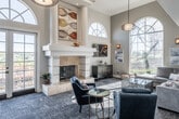 Located at 30252 Pacific Island Dr in Laguna Niguel, CA, this single-floor space combines elegant design with functional living. The centerpiece is a dramatic living room distinguished by soaring double-height ceilings, ornate crown molding, and a striking floor-to-ceiling fireplace clad in light stone. Towering arched windows flood the space with natural light while framing lush outdoor views, creating a bright and airy atmosphere. A built-in window seat offers a comfortable vantage point, and stylish pendant lighting adds a decorative focal point overhead. The living area is complemented by a warm entryway featuring rich hardwood flooring, glazed French doors, and high ceilings that reinforce the sense of openness throughout. The kitchen is efficiently designed with crisp white shaker cabinetry, dark countertops, a light subway tile backsplash, and a full suite of stainless steel appliances including a refrigerator, dishwasher, and microwave. A peninsula with a stone-look countertop provides additional workspace and transitions smoothly into the main living area. Together, these spaces deliver a cohesive, well-lit environment that balances sophisticated architectural detail with everyday practicality.
