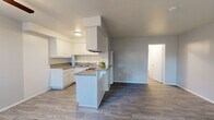 Located at 841 W La Habra Blvd in La Habra, California, this well-appointed one-bedroom, one-bathroom unit offers a thoughtfully designed layout across a single floor. The open-concept living and kitchen area creates a bright, airy feel, with large windows allowing natural light to fill the space. Sliding doors lead to a private patio, adding an inviting outdoor extension to the living area. The kitchen is a functional highlight, featuring crisp white cabinetry, granite-style countertops, a gas range, and a peninsula that seamlessly connects to the living area — ideal for both cooking and casual dining. Durable hardwood-style flooring flows throughout the main living spaces, while the bedroom features warm, plush carpeting underfoot. The generously sized primary bedroom includes a ceiling fan, a sliding-door closet with built-in shelving, and ample room for furnishings. A hallway connects the living areas to the full bathroom, which is finished with a granite vanity countertop, a tub/shower combination, and a frosted window for natural light and privacy. The overall palette of soft grays and crisp whites gives the space a clean, modern ambiance throughout.