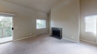 This two-story home in Tacoma, Washington offers a thoughtfully designed layout spread across two levels, connected by a carpeted staircase with a clean white railing and handrail. The main level features a kitchen equipped with dark espresso cabinetry, light stone countertops, stainless steel appliances including a full-size refrigerator, and wood-look plank flooring that extends through the adjacent areas. A bathroom on this level includes a dark-framed vanity with a white countertop, wood-look flooring, and a shower with a curtain enclosure.

The upper level showcases vaulted ceilings in at least one bedroom, adding a sense of openness and volume to the space. Bedrooms are carpeted and feature windows with blinds that allow natural light, along with baseboard heating units. Closet space is well-represented, with one bedroom featuring a sliding-door closet and another offering a walk-in closet with built-in shelving and hanging rods. A vanity area with dark cabinetry and a framed mirror accompanies the walk-in closet. Throughout, the neutral color palette of warm beige and white tones creates a calm, cohesive aesthetic across both floors.