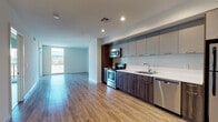 Located at 1515 Wilshire Blvd in the heart of Los Angeles, this modern single-floor unit offers a clean, contemporary design with an open-concept layout that maximizes the sense of space and light. Warm hardwood-style flooring flows throughout, tying together the living, dining, and kitchen areas seamlessly.

The kitchen is a standout feature, showcasing a full suite of stainless steel appliances including an electric range, over-the-range microwave, dishwasher, and refrigerator. Sleek two-tone cabinetry — combining matte grey upper cabinets with dark wood-grain lower cabinets — pairs with white countertops to create a polished, modern aesthetic. Recessed lighting illuminates the space efficiently.

The open living area is bright and airy, benefiting from large windows and a sliding glass door that leads to a private balcony overlooking the surrounding Los Angeles cityscape, allowing for an abundance of natural light and urban views.

The bathroom is well-appointed with a full soaking tub and shower combination, complemented by neutral tile surround and recessed lighting, maintaining the unit's consistent modern aesthetic. Throughout the space, the clean white walls and minimalist design create a versatile, move-in ready environment well-suited to urban living in the Westlake neighborhood of Los Angeles.