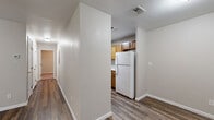 Located at 2001 Slayden St in Brownwood, Texas, this 2-bedroom, 2-bathroom unit offers a practical and well-organized single-floor layout. The combined living, dining, and kitchen area forms an open-concept hub at the heart of the unit. Rich, dark wood-look plank flooring flows through the main living spaces, anchored by a front entry door and a window that brings in natural light. The galley-style kitchen is efficiently designed with warm oak cabinetry extending to the upper walls, a full suite of white appliances including a refrigerator and electric range, a double-basin sink, and a tile backsplash that complements the neutral palette throughout. Both bedrooms are carpeted for comfort and are equipped with ceiling fans. Each bedroom benefits from direct access to a bathroom — featuring wood-toned vanities with granite-style countertops — and generously sized closets. With four closets total across the unit, storage is a notable strength of this floor plan. The bathrooms include tub-shower combinations with clean white tile surrounds. Neutral wall tones and consistent finishes throughout give the unit a cohesive, move-in-ready appearance well-suited for everyday living.