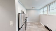 Located at 74 Claremont Gardens in Ossining, NY, this one-bedroom, one-bathroom unit offers a well-organized, single-level layout designed for comfortable everyday living. The generously sized primary bedroom features soft carpeting, neutral gray walls, a textured ceiling, and a sliding glass door that opens directly to a private outdoor area with views of surrounding greenery — a standout feature that brings natural light and a seamless indoor-outdoor connection. Two closets provide ample storage throughout the unit. The kitchen is thoughtfully updated with stainless steel appliances including a refrigerator, gas range, and over-the-range microwave, complemented by crisp white cabinetry, a subway tile backsplash, and light wood-tone vinyl flooring. A bright dining or flex area adjacent to the kitchen benefits from additional natural light through sizable windows with blinds and includes a baseboard heating unit. The bathroom is clean and modern, featuring a wood-toned vanity with a white countertop, mirrored medicine cabinet, tiled shower surround, and warm overhead lighting. A hallway connects the rooms efficiently, completing the functional and cohesive floor plan of this Ossining residence.