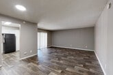 Located at 10025 E Girard Ave in Denver, CO, this single-floor, 3-bedroom, 1-bathroom unit offers a practical and well-appointed layout. The living room is a generous, open space finished with rich wood-look flooring and neutral gray walls, anchored by a textured ceiling. A sliding glass door fitted with vertical blinds fills the room with natural light while providing access to an outdoor area. The living room flows conveniently toward the kitchen, which features white shaker-style cabinetry, light granite-look countertops, and wood-look tile flooring — creating a clean, modern aesthetic. The three bedrooms are carpeted for comfort, with neutral tones and windows that bring in natural light. The primary bedroom offers a notably roomy footprint. A carpeted hallway connects the bedrooms and leads to the full bathroom, which includes a tub/shower combo, a white vanity with stone-look countertop, and wood-look tile flooring. A closet off the hallway provides additional storage. The entryway features durable wood-look flooring that carries throughout the main living areas, and the unit's overall neutral color palette creates a cohesive, move-in-ready feel throughout.