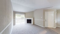 This single-story, one-bedroom, one-bathroom residence in Memphis, Tennessee offers a well-organized layout designed to maximize functionality. The living room serves as the centerpiece of the unit, featuring vaulted ceilings that lend a sense of openness and a white-mantled fireplace that adds a focal point to the space. Neutral-toned carpet and warm beige walls create a calm, cohesive atmosphere, while a large sliding glass door leads to a private balcony, allowing natural light to fill the room and providing pleasant outdoor views of surrounding greenery. A decorative chair rail runs along the walls, adding a subtle architectural detail throughout the living and dining areas.

The dining area connects seamlessly to the kitchen via a pass-through window, enhancing the open feel between spaces. The galley-style kitchen is efficiently designed, featuring white cabinetry with modern hardware, granite-look countertops, wood-look flooring, and black appliances including a range, microwave, refrigerator, and dishwasher. Track lighting overhead provides ample task illumination.

The bedroom is a comfortable, carpeted retreat with a window that admits natural light. The bathroom includes a full tub-shower combination with clean white tile surround, complemented by wood-look flooring and a vanity with ample storage.