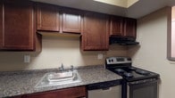Located at 2233 Courtside Dr in Columbus, Ohio, this single-floor unit offers a practical and comfortable layout designed for everyday living. The kitchen is a standout feature, showcasing rich dark cherry cabinetry that extends to the upper walls for generous storage. Granite-style countertops provide ample prep space, complemented by a stainless steel sink, electric range with overhead ventilation, stainless steel refrigerator, and a dishwasher — making the kitchen both functional and well-appointed. Wood-look flooring grounds the kitchen area, adding a warm, cohesive aesthetic.

A peninsula-style counter connects the kitchen to the living area, creating an open-concept flow between the two spaces. The living area is generously sized, carpeted, and bathed in natural light through a sliding glass door that opens to an outdoor view, enhancing the sense of openness. A wall-mounted air conditioning unit and baseboard heating ensure year-round comfort.

The bedroom is carpeted and features a window with natural light, a wall unit for cooling, and baseboard heating. The bathroom is straightforward, with wood-look flooring, a shower/tub combination, and overhead lighting. Overall, the space presents a clean, functional environment with consistent neutral tones throughout.