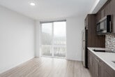 This single-floor unit showcases a cohesive modern design throughout its thoughtfully arranged spaces. The kitchen is a standout feature, outfitted with rich dark wood cabinetry extending floor to ceiling, stainless steel appliances including a full-size refrigerator and built-in microwave, light quartz countertops, and an eye-catching mosaic tile backsplash in a pattern of red, black, white, and grey — a detail that adds artistic character to the space.

The living area is bright and open, benefiting from a floor-to-ceiling glass sliding door that frames urban views and draws in generous natural light. Light-toned hardwood-style flooring runs throughout the main living spaces, contributing to the unit's clean, contemporary aesthetic.

The bathroom continues the mosaic tile motif, featuring a full soaking tub and shower combination enclosed by large-format white subway tiles. A striking vertical mosaic tile accent strip — mirroring the kitchen backsplash design — serves as a bold focal point. Dark slate-style floor tiles ground the bathroom space with contrast and texture.

A small utility panel is conveniently recessed into the hallway wall, and the overall layout, as revealed by the 3D scan, flows efficiently from the entry through the main living and kitchen areas toward the bathroom.
