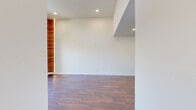 Located at 16550 Vanowen St in Van Nuys, Los Angeles, this thoughtfully designed one-bedroom, one-bathroom unit offers a clean, modern aesthetic throughout its efficiently laid-out single floor. Rich hardwood-style flooring flows consistently across the living spaces, anchoring the bright, neutral palette of crisp white walls and trim.

The combined kitchen and living area forms the heart of the unit. The galley-style kitchen is well-appointed with white shaker cabinetry, white quartz countertops, a classic subway tile backsplash, and a full suite of stainless steel appliances including a gas range, dishwasher, and refrigerator. A window above the sink invites natural light into the space.

The living area is notably airy, benefiting from soaring ceilings and a distinctive vertical wood accent column with integrated accent lighting — a striking architectural detail that adds warmth and character. Large sliding glass doors open directly onto a private balcony, offering open views of the surrounding neighborhood and bringing in abundant natural light.

The bedroom is a comfortable, well-proportioned retreat featuring upper cabinetry for additional storage and a window with curtains. The bathroom is finished in a clean, contemporary style with large-format white wall tiles, a soaking tub with shower, and brushed nickel fixtures. The unit is completed by an entrance hallway that provides a smooth transition into the living spaces.