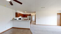 Located at 3405 Logan Dr in Oshkosh, Wisconsin, this well-appointed 2-bedroom, 1-bathroom home offers a functional and comfortable single-floor layout. The open-concept design seamlessly connects the kitchen and living area, creating an inviting communal space. The kitchen is a standout feature, equipped with rich cherry wood cabinetry, stainless steel appliances including a refrigerator and range, a peninsula with a countertop overhang ideal for casual dining, and durable wood-style flooring. The living area flows naturally from the kitchen, offering plush carpeting underfoot and access to a private balcony through sliding glass doors that bring in generous natural light. Both bedrooms are carpeted and bright, each featuring windows with outdoor views and ample wall space. The primary bedroom includes access to a dedicated closet and a nearby full bathroom. The bathroom is finished with tile flooring, a single-sink vanity with matching cabinetry, and a full tub-shower combination. Throughout the home, warm wood-tone door frames and trim provide a cohesive aesthetic against the clean white walls, resulting in a bright and practical living environment.