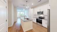 Located at 1300 Hendricks Ave in Jacksonville, Florida, this thoughtfully designed one-bedroom, one-bathroom residence offers a efficient and comfortable single-floor layout. The kitchen serves as the centerpiece of the home, showcasing a large island with a granite countertop and an undermount sink, white shaker-style cabinetry, a classic subway tile backsplash, and a full suite of stainless steel appliances. Stylish pendant lighting and recessed fixtures illuminate the space, while warm hardwood-style flooring flows throughout. The kitchen opens toward the living area, which is brightened by large windows and a ceiling fan, creating an airy, connected feel. The bedroom is carpeted for comfort and features multiple windows with horizontal blinds that frame views of palm trees and the surrounding Jacksonville skyline, inviting generous natural light. The bathroom is well-finished with a granite-topped vanity, hardwood-style flooring, and a glass-enclosed shower. A dedicated in-unit laundry area adds everyday convenience. Throughout the residence, neutral tones, clean white walls, and quality materials contribute to a cohesive, modern aesthetic that is both functional and inviting.
