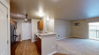 Located in Spokane, WA, this single-floor residence offers three bedrooms and two bathrooms within a well-organized, functional floor plan. The open-concept kitchen and living area serves as the heart of the home, where warm wood cabinetry, light countertops, and a peninsula with a double sink create a practical and inviting cooking space. Track lighting illuminates the kitchen, which is equipped with black appliances including a refrigerator, range, and microwave. A convenient walk-in pantry adds generous storage. Hardwood-style flooring runs through the kitchen, transitioning to plush carpet in the living room and bedrooms. The spacious living room features a sliding glass door that opens to a patio, filling the space with natural light and providing outdoor access. Each bedroom is carpeted and includes a closet with arched panel doors, offering ample storage. Secondary bedrooms feature large windows that bring in natural light. Both bathrooms are finished with wood-tone vanities and light countertops; one includes a baseboard heater, while the other features a full tub-shower combination. Neutral warm beige tones carry throughout the residence, creating a cohesive and comfortable ambiance.