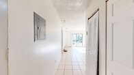 This three-bedroom, two-bathroom single-floor residence in Hialeah, Florida offers a functional and straightforward layout across a compact but efficiently utilized footprint. Light-toned ceramic tile flooring runs consistently throughout the home, lending a cohesive and easy-to-maintain aesthetic to every room.

The living and dining areas are connected in an open arrangement, with the dining space featuring a decorative pendant light fixture. A sliding glass door in the living area floods the space with natural light and opens onto a balcony, which provides outdoor views of the surrounding neighborhood and greenery.

The kitchen is equipped with white cabinetry extending to the ceiling for ample storage, a stainless steel sink, a coil-burner range, and a refrigerator, all set against light tile floors.

The primary bedroom is generously sized and includes multiple louvered closet doors offering abundant storage. The two additional bedrooms are bright and well-proportioned, each with windows that bring in natural light. A hallway connects the main living spaces to the bedrooms.

Both bathrooms feature full tub-shower combinations with tiled surrounds. One bathroom includes a window for natural ventilation. A dedicated laundry area completes the layout, adding practical convenience to this well-organized Hialeah residence.