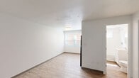 Located at 862 Asylum Ave in Hartford, Connecticut, this single-floor studio unit offers a thoughtfully organized layout that makes efficient use of its compact footprint. The main living area features light wood-style laminate flooring, crisp white walls, and neutral baseboards that create a clean, modern aesthetic throughout. Natural light filters in through blinded windows, lending the space a bright and airy feel. A wall-mounted mini-split air conditioning unit ensures year-round comfort, and a smoke detector is installed for safety.

The kitchen is well-appointed with rich dark-wood cabinetry both above and below the counter, providing ample storage. Black appliances — including a range with coil burners, a range hood, and a full-size refrigerator — complement the countertop and single-basin sink. A window above the counter further brightens the cooking space.

The bathroom is finished in a clean, all-white palette, featuring a soaking tub with a shower and curtain rod, a white vanity with an undermount sink, a mirrored medicine cabinet, and a small window that allows natural ventilation. Wood-style flooring continues into this space, maintaining visual consistency. The unit's straightforward layout and functional finishes make it a practical and well-maintained living space.