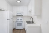Located at 440 Canyon Drive in Oceanside, CA, this one-bedroom, one-bathroom residence offers a well-organized single-floor layout with a clean, neutral aesthetic throughout. Light wood laminate flooring runs continuously across the living spaces, complemented by textured ceilings and crisp white walls that create a bright, cohesive feel.

The open-concept living, dining, and kitchen area serves as the heart of the home. The living room is generously sized and bathed in natural light from a large sliding glass door that opens directly onto a private balcony, offering pleasant outdoor views of the surrounding hillside landscape. A ceiling fan adds comfort to the space. The galley-style kitchen is efficiently designed with white cabinetry extending to the ceiling for ample storage, light countertops, a stainless steel sink, and white appliances including a refrigerator, gas range, and built-in microwave.

The spacious bedroom features a natural light-filled window, a textured ceiling, and a wide mirrored sliding closet. Additional closet space is available throughout the unit, totaling three closets. The bathroom includes a wide vanity with a large mirror, light countertops, and stylish pendant lighting. An entrance, hallway, and thoughtful layout complete this well-appointed Oceanside residence.