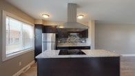 Located at 2745 Coldstream Ln in Columbus, Ohio, this three-floor home offers a well-appointed layout with thoughtfully updated finishes throughout. The kitchen serves as a standout feature, showcasing dark espresso cabinetry, granite countertops, a stainless steel refrigerator, a sleek island with a built-in cooktop, a mosaic tile backsplash, and a prominent stainless steel range hood that anchors the space. Light hardwood-style flooring extends through the main living areas, complementing the neutral warm-gray walls and creating a cohesive, modern aesthetic. The open living area flows naturally from the kitchen, providing generous room for flexible use. Bedrooms are finished with plush carpeting and feature windows that allow natural light to filter in, along with closet access. Bathrooms include a half bath with a wall-mounted sink and mirror, as well as a full bath with a tub-shower combination and tile flooring. The lower level offers a spacious finished bonus room with wood-style flooring and a small window, alongside a dedicated laundry area equipped with a full-size washer and dryer and a utility sink, providing practical everyday functionality.