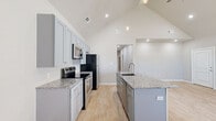 Located in Centerton, Arkansas, this single-story home offers a thoughtfully designed layout across three bedrooms and three full bathrooms. Light-toned wood-style flooring runs consistently throughout, complementing the neutral gray walls and white trim to create a clean, cohesive aesthetic.

The open kitchen and living area serves as the heart of the home, featuring soaring vaulted ceilings with recessed and pendant lighting. The kitchen is outfitted with gray shaker-style cabinetry, granite countertops, stainless steel appliances, and a central island with a sink — providing ample workspace and storage. The adjacent living area benefits from natural light through front-facing windows.

Each bedroom includes a ceiling fan and dedicated closet space. The primary bedroom features an en-suite bathroom with a double-sink granite vanity, gray cabinetry, and LED-lit mirrors, alongside a generously sized walk-in closet with built-in shelving and hanging rails. Secondary bathrooms include tub/shower combinations. A dedicated laundry area accommodates a full-size washer and dryer with overhead shelving. The hallway connects all rooms efficiently, completing this well-organized single-floor layout.