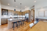 Located in Elkhorn, Nebraska, this well-appointed two-story home offers four bedrooms, three bathrooms, and a thoughtfully designed layout spread across two floors. The main level provides a compact yet functional footprint, while the upper level delivers the majority of the living space.

The kitchen is a standout feature, showcasing warm-toned shaker cabinetry, a large center island with a quartz countertop and built-in sink, stainless steel appliances, a white subway tile backsplash, and pendant lighting — all set atop light hardwood flooring. The adjacent living room benefits from large windows that flood the space with natural light and offer views of the surrounding neighborhood.

The generously sized primary bedroom includes direct access to a private balcony and leads to a spacious walk-in closet outfitted with custom shelving and dual hanging rods. The bathrooms are finished with large-format tile flooring, warm wood vanities, white quartz countertops, and matte black hardware and fixtures, lending a modern yet timeless aesthetic throughout.

Additional bedrooms are bright and well-proportioned, with large windows providing ample natural light. A dedicated laundry room includes upper cabinetry for storage and comes equipped with a full-size washer and dryer. The attached garage completes this home with practical, everyday convenience.