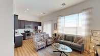Located in Mesa, Arizona, this single-story residence offers a well-designed open-concept layout that seamlessly connects the living, dining, and kitchen areas. Light wood-look flooring runs throughout the main living spaces, complementing the bright, neutral color palette and creating a cohesive, modern aesthetic.

The kitchen is outfitted with rich dark-espresso cabinetry extending to the ceiling for ample storage, white countertops, and a full suite of stainless steel appliances including a range, over-the-range microwave, and refrigerator. A dining area adjacent to the kitchen provides a dedicated space for meals. Large windows with vertical blinds and sheer curtains flood the open living area with abundant natural light, creating an inviting atmosphere throughout the day.

The primary bedroom is a comfortable retreat featuring elevated clerestory windows that introduce additional natural light while maintaining privacy. It connects directly to an en-suite bathroom appointed with dark cabinetry, a white countertop vanity, a large wall mirror, and a tiled walk-in shower. A second bedroom offers versatile flex space with its own window and natural light. The second bathroom features a tub-shower combination, white countertop vanity, and a small privacy window. Recessed lighting and consistent finishes tie the entire residence together cohesively.