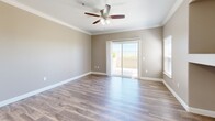 This well-appointed 3-bedroom, 2-bathroom single-story home in Elk Grove, California offers a thoughtfully designed layout with a comfortable flow throughout. The open kitchen is a standout feature, equipped with stainless steel appliances including a range, microwave, and refrigerator, complemented by crisp white cabinetry, light quartz countertops, a central island with a sink, and wood-look flooring that extends into the living area. The living room is bright and inviting, featuring crown molding, a ceiling fan, and a sliding glass door that opens to a private patio with outdoor views, allowing abundant natural light to fill the space. A built-in recessed nook adds a functional architectural detail to the living area. The three bedrooms are carpeted for warmth and comfort, each with clean neutral walls and panel-style doors. The spacious primary bedroom includes a dedicated walk-in closet with wire shelving. Both bathrooms are finished with white cabinetry, quartz-style vanities, brushed nickel fixtures, and tub-shower combinations with wood-look flooring. A dedicated laundry room houses a full-size washer and dryer with overhead cabinetry for additional storage. Throughout the home, consistent warm-toned walls, white trim, and wood-look flooring create a cohesive, modern aesthetic.