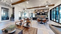 Located in Phoenix, AZ, this thoughtfully designed single-floor clubhouse blends rustic warmth with contemporary sophistication across a generously sized footprint. The entry welcomes visitors with light hardwood herringbone flooring, curated geometric wall art, and sleek black-framed glass doors that set an immediate tone of modern refinement.

The main lounge area is a standout, anchored by a full brick fireplace flanked by reclaimed wood accent walls with built-in black display niches showcasing sculptural décor. Exposed wooden ceiling beams and geometric pendant chandeliers add architectural character, while plush seating arrangements invite relaxed gathering. A wall-mounted TV completes the entertainment-focused layout.

A second lounge and dining area flows seamlessly from the main space, featuring a bar-style counter with pendant lighting, mixed seating for casual dining, and a billiards table — all bathed in natural light from expansive black-framed windows with views of the surrounding landscape.

The private office provides a focused workspace with built-in L-shaped desks, ample drawer storage, and bright natural light. An additional meeting room offers a round table, lounge seating, and accent wall, ideal for small group gatherings. Throughout, the design balances industrial-rustic materials with warm, curated furnishings for a cohesive and inviting atmosphere.