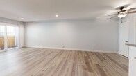 Located at 6317 Monterey Rd in Los Angeles, this one-bedroom, one-bathroom unit offers a thoughtfully laid-out single-floor plan with consistent wood-look flooring throughout. The open living room is bright and airy, featuring recessed lighting, a wall-mounted AC unit, and a sliding glass door that opens to a private fenced outdoor area, allowing natural light to fill the space. The galley-style kitchen is well-appointed with rich warm-toned wood cabinetry, granite countertops, a mosaic tile backsplash, and stainless steel appliances including a gas range and refrigerator. A peninsula counter with additional storage provides a natural division between the kitchen and the entryway. The bedroom offers a comfortable footprint with mirrored sliding closet doors that enhance the sense of space, neutral gray walls, and wood-look flooring. A window with vertical blinds brings in natural light. The full bathroom features large-format neutral tile surrounding the soaking tub and shower combination, wood-look flooring, and a granite-topped vanity. A hallway connects the main living areas, completing the efficient and functional layout of this Los Angeles unit.