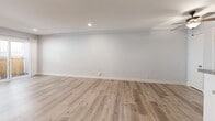 Located at 6317 Monterey Rd in Los Angeles, this one-bedroom, one-bathroom unit offers a thoughtfully laid-out single-floor plan with consistent wood-look flooring throughout. The open living room is bright and airy, featuring recessed lighting, a wall-mounted AC unit, and a sliding glass door that opens to a private fenced outdoor area, allowing natural light to fill the space. The galley-style kitchen is well-appointed with rich warm-toned wood cabinetry, granite countertops, a mosaic tile backsplash, and stainless steel appliances including a gas range and refrigerator. A peninsula counter with additional storage provides a natural division between the kitchen and the entryway. The bedroom offers a comfortable footprint with mirrored sliding closet doors that enhance the sense of space, neutral gray walls, and wood-look flooring. A window with vertical blinds brings in natural light. The full bathroom features large-format neutral tile surrounding the soaking tub and shower combination, wood-look flooring, and a granite-topped vanity. A hallway connects the main living areas, completing the efficient and functional layout of this Los Angeles unit.