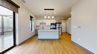 Located at 2171 E 103rd St in Cleveland, Ohio, this modern 2-bedroom, 3-bathroom unit offers a thoughtfully designed single-floor layout with contemporary finishes throughout. Light-toned luxury vinyl plank flooring flows consistently across all rooms, creating a cohesive and clean aesthetic.

The open-concept kitchen and living area serves as the heart of the unit. The kitchen is outfitted with white upper shaker cabinets, gray lower cabinets, quartz countertops, a black matte faucet, and a full suite of stainless steel appliances including a refrigerator, range, microwave, and dishwasher. A central island with a light countertop provides additional prep space and seating, finished with globe pendant lighting above.

The spacious primary bedroom features multiple black-framed windows offering urban views and abundant natural light, while the secondary bedroom includes its own window with a ceiling fan fixture. A well-lit hallway connects the private spaces, with recessed lighting overhead and access to ample closet storage.

The three bathrooms reflect consistent modern design — one features a soaking tub with white surround and a gray vanity with black hardware, while another offers a walk-in shower enclosed by bold black-framed glass doors. Neutral wall tones and clean lines define the overall ambiance of this well-appointed unit.