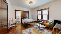 Located at 1507 Spruce Pl in Minneapolis, MN, this single-floor studio unit blends vintage charm with functional living. The entryway greets visitors with warm hardwood floors and rich, dark wood door frames and trim that carry throughout the space, lending a classic character consistent with the building's historic aesthetic.

The main living area serves as the heart of the unit, combining sleeping and sitting functions in an open layout. Natural light filters in through windows dressed with blinds, illuminating the hardwood floors below. A ceiling-mounted light fixture adds a touch of vintage elegance to the room.

Adjacent to the main room, a compact kitchenette area features bold black-and-white checkered tile flooring, white wainscoting, a wall-mounted utility sink, and a full-size refrigerator — providing essential functionality within a modest footprint.

The bathroom is a standout feature of the unit, showcasing a classic clawfoot soaking tub with an overhead shower, a pedestal sink, a medicine cabinet, and white hexagonal mosaic tile flooring. The crisp white walls and traditional fixtures give the bathroom a timeless, vintage appeal.

Rich wood millwork, original hardwood floors, and period-appropriate fixtures throughout create a cohesive, character-filled living space that reflects the historic architecture of the Minneapolis neighborhood it calls home.