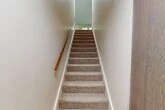 Located at 825 Tamarack Dr in West Carthage, NY, this two-story home offers a practical and comfortable layout across two levels. The main living floor hosts the majority of the space, including a bright, generously sized living room with large windows and a sliding glass door that fills the area with natural light and provides outdoor views. The kitchen is well-equipped with warm oak cabinetry, dark laminate countertops, a double sink, a dishwasher, electric range, and a refrigerator, all set on easy-care flooring with a window overlooking the greenery outside. Two carpeted bedrooms offer comfortable retreats, each featuring natural light from double windows and baseboard heating. The primary bedroom provides a notably spacious footprint. The full bathroom includes a tub-shower combination, a vanity with an oak medicine cabinet, and tile-style flooring. Four closets throughout the home offer ample storage. A carpeted staircase with a wooden handrail connects the floors. The attached garage features a concrete floor, OSB-paneled walls, and an overhead door, providing secure parking and additional storage. A utility room rounds out the home's functional offerings.