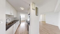 Located on the 14th floor at 86 Cedar Street South in Kitchener, Ontario, this well-appointed 2-bedroom, 1-bathroom unit offers a clean, modern aesthetic throughout. Light wood laminate flooring runs seamlessly across all rooms, complementing the crisp white walls and creating a bright, cohesive feel.

The open-concept kitchen and living area forms the heart of the unit. The kitchen is equipped with white cabinetry, dark countertops, a white subway tile backsplash, and stainless steel appliances including a refrigerator and dishwasher. The generous living area flows naturally from the kitchen, providing ample space for everyday living.

The primary bedroom is a well-sized retreat featuring a large sliding closet, access to a private balcony, and windows that frame elevated city and treetop views. The second bedroom is also bright and comfortable, with a window allowing natural light to fill the room.

Both bedrooms benefit from the light-filled, airy atmosphere consistent throughout the unit. The bathroom is finished with classic white subway tile surrounding a full soaker tub and shower combination with chrome fixtures. A hallway connects all rooms efficiently, completing the functional layout. This unit offers a comfortable, modern living experience in a high-floor setting.