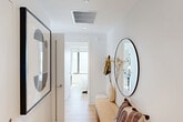 Located at 1070 Bridgeview Way in San Francisco's Mission Bay neighborhood, this thoughtfully designed two-bedroom, two-bathroom residence offers a cohesive modern aesthetic throughout. The layout is organized efficiently across a single floor, with a welcoming hallway that leads to the main living areas. The hallway features light wood flooring, crisp white walls, and stylish accents including a round mirror and a cushioned bench, setting the tone for the rest of the home.

Both bedrooms are bright and well-appointed, each offering large picture windows that frame sweeping views of the San Francisco Bay and the waterfront pier below — a standout feature of this residence. The primary bedroom includes a full-length mirror and direct sightlines to the kitchen, which is outfitted with light wood cabinetry, subway tile backsplash, and a professional-grade range.

The two bathrooms are finished with clean, contemporary materials. The primary bathroom features a glass-enclosed walk-in shower with floor-to-ceiling tile, a wall-hung vanity with light wood drawers, and a backlit mirror. The second bathroom mirrors the same refined aesthetic with a matching vanity and backlit mirror.

Light wood flooring, recessed lighting, and a neutral white palette unify the space, creating a calm, modern ambiance throughout.