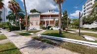 Located at 656 Beach Dr NE in the vibrant waterfront neighborhood of Saint Petersburg, Florida, this utility space serves as a dedicated laundry facility. The single-room interior features a clean, functional layout with exposed overhead ductwork and copper piping that give the space an industrial character. The epoxy-speckled floor is durable and easy to maintain, and the room accommodates multiple sets of top-loading washers and dryers, along with a stainless steel refrigerator and a decorative indoor plant that adds a touch of warmth to the utilitarian setting. An electrical panel and ventilation components are neatly integrated into the space. Access is provided through a bold black door. Outside, the property is framed by mature palm trees, lush greenery, and decorative stone-paved walkways that reflect the charm of the surrounding Beach Drive corridor. The neighborhood context is notably scenic, with tree-lined sidewalks, neighboring mid-century and modern residential buildings, and a relaxed Florida coastal atmosphere. A warm-toned wood and glass fence adds a contemporary touch to the building's exterior, complementing the brick and siding facade. The location offers a walkable, vibrant setting in one of St. Petersburg's most desirable waterfront districts.
