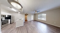 Located at 8585 Spicewood Springs Rd in Austin, TX, this well-appointed one-bedroom, one-bathroom residence offers a thoughtfully designed single-level layout. The open-concept living room greets you with warm hardwood-style flooring, crown molding, a ceiling fan, and generous natural light streaming through large windows, including a charming arched window that frames outdoor greenery. A front door with glass panels adds additional brightness to the welcoming space. The kitchen flows seamlessly from the living area and is equipped with stainless steel appliances — including a range, microwave, and refrigerator — white cabinetry, and a peninsula featuring a double-basin sink and light quartz countertops, ideal for both cooking and casual dining. The bedroom is a comfortable retreat with plush wall-to-wall carpeting, a ceiling fan, and a window with outdoor views, complemented by a dedicated closet for ample storage. The bathroom features a full tiled tub-shower combination, a toilet, and wood-style flooring, maintaining the clean, neutral aesthetic found throughout. A hallway connects the rooms efficiently, completing this cohesive and functional layout suited for comfortable everyday living in Austin.