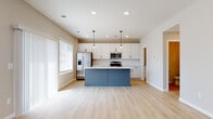 This two-story home is designed with a clean, contemporary aesthetic that balances functionality and modern style. The kitchen serves as a standout feature, showcasing white shaker cabinetry that extends to the ceiling, a classic white subway tile backsplash, and stainless steel appliances including a gas range, microwave, and French door refrigerator. A large center island with a slate-blue base and crisp white countertop provides both workspace and casual seating, illuminated by stylish pendant lighting. Light wood-look flooring runs throughout the main level, lending warmth and continuity to the open layout.

The bedrooms are generously proportioned, carpeted in soft grey, and benefit from abundant natural light through multiple windows. The primary bedroom features a ceiling fan and direct access to an en-suite bathroom with cabinetry and vanity. Additional bedrooms offer similar comfort with wide windows and neutral tones. A compact half bathroom on the main level includes a pedestal sink and grab bar, while a full bathroom features a soaking tub and shower surround. A dedicated laundry room accommodates a full-size washer and dryer with overhead wire shelving, completing the home's practical layout.