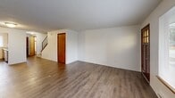 This two-bedroom, two-bathroom unit in Tacoma, Washington is spread across two floors, offering a practical and well-organized layout. The main floor welcomes you through a warm wood-panel front door with glass transom detail, opening into a spacious combined living and dining area. This open space features wood-look flooring, a textured ceiling, baseboard heating, and a large picture window that fills the room with natural light and views of the surrounding neighborhood. The kitchen is adjacent to the living area and is equipped with warm wood cabinetry, light laminate countertops, a stainless steel sink, and a dishwasher, alongside a window that brings in additional natural light. A hallway and staircase connect the main floor to the upper level, where both bedrooms are located. Each bedroom features wood-look flooring, textured ceilings, baseboard heating, and windows that offer outdoor views. The primary bedroom provides a comfortable, well-proportioned retreat. The two bathrooms include a full bath with a tub/shower combination, and a second bathroom that also accommodates laundry. Three closets provide ample storage throughout. The unit's consistent flooring, neutral palette, and functional design create a cohesive and livable environment.