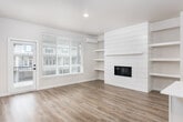 This three-story home offers a well-designed layout spread across multiple levels, connected by a carpeted staircase with a clean white railing system. The main living level features wood-look flooring throughout, anchored by an open-concept kitchen equipped with white shaker-style cabinetry, subway tile backsplash, light countertops, a stainless steel French door refrigerator, and a central island with a pendant-lit chandelier and undermount sink. The open layout allows the kitchen to flow naturally toward the living area, which is brightened by large windows with white blinds.

The bathrooms maintain a consistent, clean aesthetic with white shaker vanities, light stone countertops, undermount sinks, large mirrors with bar lighting, black hardware accents, and wood-look flooring. One bathroom includes a full soaking tub/shower combo with a small privacy window for natural light.

Bedrooms are carpeted and offer a comfortable, neutral atmosphere with natural light provided by windows fitted with white blinds. A dedicated laundry room houses a full-size washer and dryer with overhead shelving. Throughout the home, neutral wall tones, white trim, and consistent finishes create a cohesive and modern aesthetic.