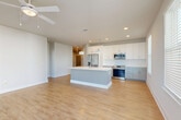 Located at 1464 Laurel Sound Lane in Sanford, FL, this well-appointed 3-bedroom, 2-bathroom home offers a thoughtfully designed single-floor layout. The open-concept living area seamlessly connects the living room, dining space, and kitchen, all finished with warm light wood-style flooring and recessed lighting throughout. The kitchen is a standout feature, boasting a center island with a sink and pendant lighting, white shaker-style cabinetry, stainless steel appliances including a range, microwave, and refrigerator, and a classic subway tile backsplash. A ceiling fan overhead enhances the airy feel of the main living area. The hallway leads to three comfortably sized bedrooms, each carpeted for warmth and comfort, with the secondary bedrooms featuring ceiling fans and generous natural light through blinds-fitted windows. The spacious primary bedroom includes a dedicated walk-in closet with wire shelving. Both bathrooms are finished with wood-look flooring, white vanities with dark countertops, and an illuminated mirror. The main bath features a tub-shower combo with large-format marble-style tile. Additional highlights include multiple closets for storage, a laundry area, a built-in mudroom nook, and a private balcony accessible from the living area.