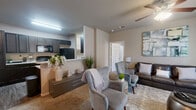 This single-story, 2-bedroom, 2-bathroom residence offers a thoughtfully designed open-concept floor plan that seamlessly connects the living room, dining area, and kitchen. The living room features plush carpeting, a ceiling fan, and neutral warm-toned walls, creating a comfortable and inviting atmosphere. The kitchen is well-equipped with dark espresso cabinetry, granite-style countertops, black appliances including a refrigerator, range, and built-in microwave, and durable wood-look flooring that extends throughout the kitchen and dining areas. A peninsula with a double basin sink adds both functionality and a natural divide between the kitchen and living spaces. The primary bedroom is a generously sized retreat with carpet flooring, a ceiling fan, and a window allowing natural light. It includes a walk-in closet with multi-rod hanging storage. The second bedroom also offers carpet flooring and ample space. Both bathrooms are finished with dark cabinetry, granite-style countertops, and tub-shower combinations. A dedicated in-unit laundry room accommodates a full-size washer and dryer with overhead shelving for added storage. Two closets throughout the unit provide excellent organization options, completing this practical and well-designed residence.