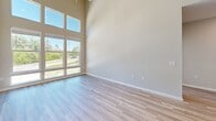 Located in Conroe, TX, this thoughtfully designed 2-bedroom, 2-bathroom residence offers a well-appointed single-level layout with impressive architectural details throughout. The open-concept living, dining, and kitchen area is the heart of the home, boasting dramatically high ceilings and expansive floor-to-ceiling windows that flood the space with natural light and offer scenic views of the surrounding greenery. Light-toned wood-look flooring runs throughout the main living areas, complementing the bright, neutral color palette. The kitchen features two-tone cabinetry — white upper cabinets paired with warm wood-grain lower cabinets — along with white quartz countertops, a subway tile backsplash, and stainless steel appliances including a dishwasher and range. A private balcony extends from the living area, adding valuable outdoor space. Both bedrooms are carpeted and include ceiling fans, with the primary bedroom offering a walk-in closet with built-in shelving and an en-suite bathroom. The primary bath includes wood-tone cabinetry, a white quartz vanity, and a separate shower. The second bathroom features a tiled tub-shower combo with a curved rod and matching modern finishes. A dedicated laundry area and additional closet storage round out this well-equipped residence.
