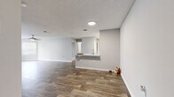 Located at 8801 Hunters Lake Dr in Tampa, FL, this two-bedroom, two-bathroom single-floor residence offers a well-designed layout with a clean, contemporary aesthetic throughout. The open-concept living and kitchen area is anchored by durable wood-look flooring and neutral gray tones, creating a bright and cohesive atmosphere. The kitchen is a functional highlight, featuring white shaker-style cabinetry, light countertops, a classic white subway tile backsplash, and a full suite of stainless steel appliances including a range, microwave, and dishwasher. A pass-through peninsula connects the kitchen to the living area, enhancing the open feel of the shared space. The primary bedroom is a comfortable retreat with plush carpeting, a ceiling fan, natural light from a window with blinds, and direct access to a spacious walk-in closet outfitted with wire shelving. The second bedroom also features carpet flooring and a window. Both bathrooms are finished with white vanities, large mirrors, and wood-look tile flooring. A dedicated laundry room houses a full-size washer and dryer. The secondary bedroom area includes a distinctive bay window configuration, allowing for ample natural light. Textured ceilings are consistent throughout the home.