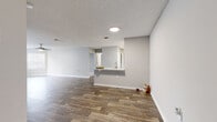 Located at 8801 Hunters Lake Dr in Tampa, FL, this two-bedroom, two-bathroom single-floor residence offers a well-designed layout with a clean, contemporary aesthetic throughout. The open-concept living and kitchen area is anchored by durable wood-look flooring and neutral gray tones, creating a bright and cohesive atmosphere. The kitchen is a functional highlight, featuring white shaker-style cabinetry, light countertops, a classic white subway tile backsplash, and a full suite of stainless steel appliances including a range, microwave, and dishwasher. A pass-through peninsula connects the kitchen to the living area, enhancing the open feel of the shared space. The primary bedroom is a comfortable retreat with plush carpeting, a ceiling fan, natural light from a window with blinds, and direct access to a spacious walk-in closet outfitted with wire shelving. The second bedroom also features carpet flooring and a window. Both bathrooms are finished with white vanities, large mirrors, and wood-look tile flooring. A dedicated laundry room houses a full-size washer and dryer. The secondary bedroom area includes a distinctive bay window configuration, allowing for ample natural light. Textured ceilings are consistent throughout the home.