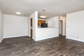 This single-floor residence offers a practical and comfortable layout designed for everyday living. The open-concept living and dining area is finished with rich, dark hardwood-style flooring that extends throughout the main living spaces, creating a cohesive and polished aesthetic. A large sliding glass door fills the living area with natural light and provides direct access to the outdoors.

The galley-style kitchen is well-equipped, featuring warm honey-toned wood cabinetry, light countertops, black appliances including an electric range and refrigerator, and a double sink. A pass-through half-wall connects the kitchen to the main living area, enhancing the open feel of the space.

The bedrooms offer plush carpeting underfoot for added comfort. Each room is generously sized and includes walk-in closet space with built-in shelving and hanging rods, providing ample storage. Ceiling fans with light fixtures add both function and airflow to the sleeping quarters, while windows allow for natural light and outdoor views.

A hallway connects the private areas of the home, leading to a bathroom appointed with a wide vanity, generous mirror, and cabinetry below. The neutral warm-beige palette throughout the residence lends a calm, versatile backdrop ready for personalization.